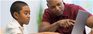 adult helping child on the laptop